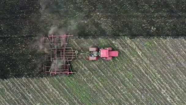 Zicht vanaf de drone: trekker ploegt veld. Camera na de trekker — Stockvideo