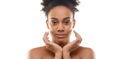 35 yaşında, beyaz tenli Afro-Amerikalı bir kadın kameraya bakıyor ve yüzüne dokunuyor..