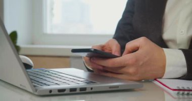 Ertelemek - Akıllı telefonlu bir kadın elleri bir dizüstü bilgisayarın önünde. Bir kadın aktif olarak çevrimiçi iletişim kurar ya da çalışma saatlerinde oynar.