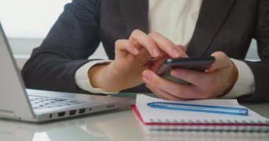 İş yerinde akıllı telefonlu bir kadının elleri var. Bir kadın mesai saatleri içinde akıllı telefondaki resimlere bakar, sever ve sever..
