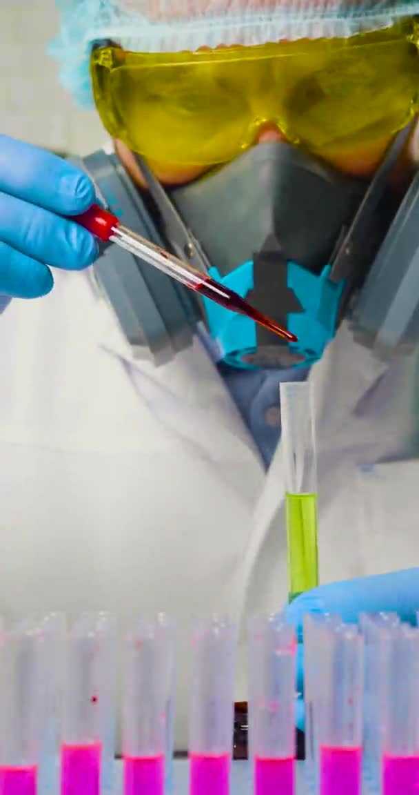 Forskare i ett labb droppar ett prov av infekterat blod i ett provrör - närbild vertikal 4k video. — Stockvideo