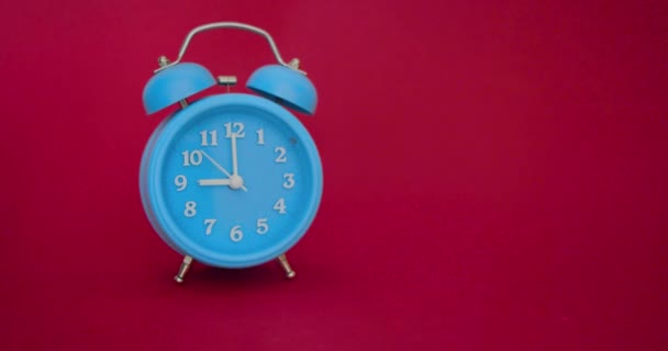 Video with sound - a blue alarm clock on a red background rings at 9 AM — Stock Video