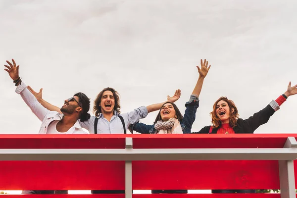 大きな赤いベンチから空に向かって叫んでいる親友のグループ — ストック写真