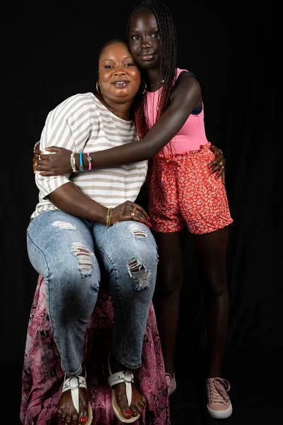 アフリカ系アメリカ人の母親と娘笑顔幸せな抱擁オン黒の背景 — ストック写真