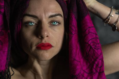 Genç ve güzel bir kadının portresi kırmızı bir atkıyla eğleniyor. Stüdyo fotoğrafı.