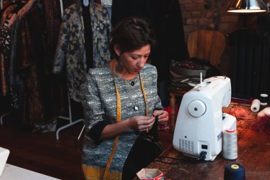 Genç terzi atölyedeki dikiş makinesiyle çalışıyor.