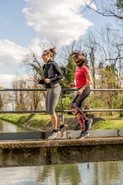 Kadınlar beton köprüde spor giyerek koşuyorlar. Sağlıklı yaşam tarzı konsepti.