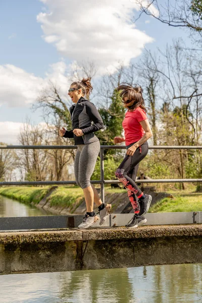 Kadınlar beton köprüde spor giyerek koşuyorlar. Sağlıklı yaşam tarzı konsepti.