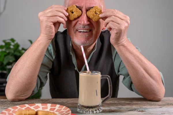 Casual Dressed Mature Man Two Cookies His Eyes Sitting Table — Foto de Stock