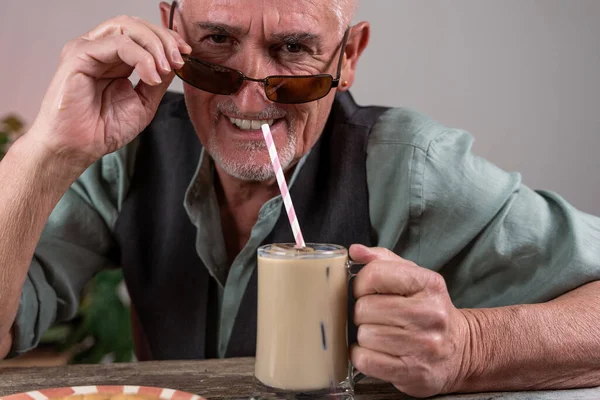 Casual Dressed Mature Man Sunglasses Sitting Table Drinking Iced Coffee — Zdjęcie stockowe