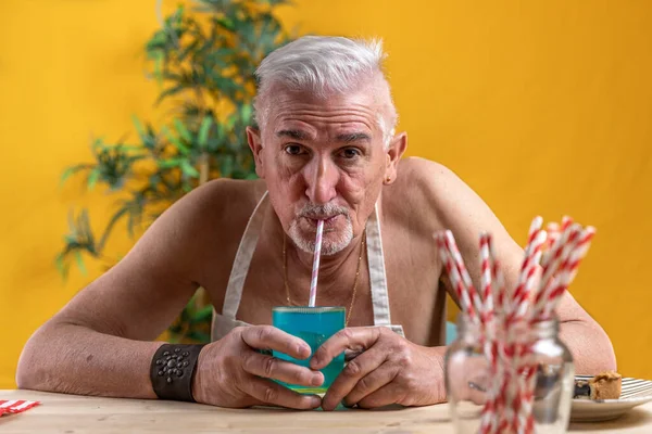 英俊的中年男人坐在桌旁 用稻草喝蓝色软饮料 彩色背景图片拍摄 — 图库照片