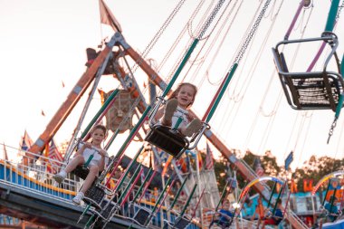 İki mutlu kız kardeş lunaparkta eğleniyor - yaz eğlencesi konsepti