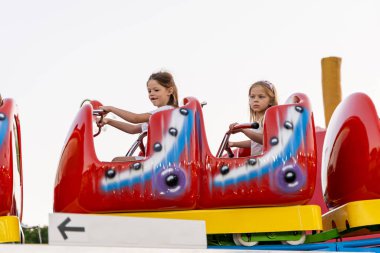 İki mutlu kız kardeş lunaparkta eğleniyor - yaz eğlencesi konsepti