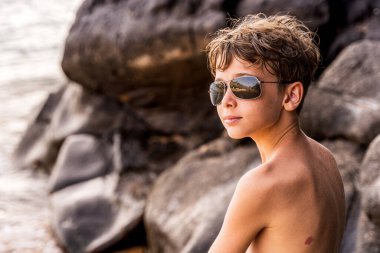 funny portrait of young shirtless man wearing sunglasses in an exotic beach - summer vacation concept