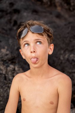 funny portrait of young shirtless man wearing sunglasses in an exotic beach - summer vacation concept