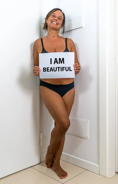 image of a beautiful middle aged woman posing in her apartment - Mature woman in black lingerie in his home - Concept about body positivity self esteem and body acceptance