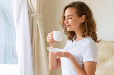 Genç bir kadın sabah uyandıktan sonra elinde kahve ya da sıcak çikolata tutarken ve içerken kendini rahat hissediyordu. Yaşam tarzı kavramı.