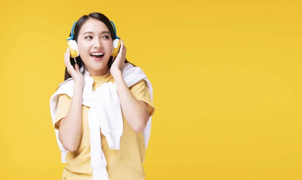 音楽を聴くヘッドフォンを装着した若い女性がスマートフォンを形成し 孤立した黄色の背景の上でリラックスして踊る陽気 趣味をコンセプトにしたライフスタイルレジャー — ストック写真