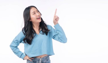 Cheerful excited asian woman use finger pointing to side with product or empty copy space standing over isolated white background. Model young girl laughing promotion. Advertisement presenting concept