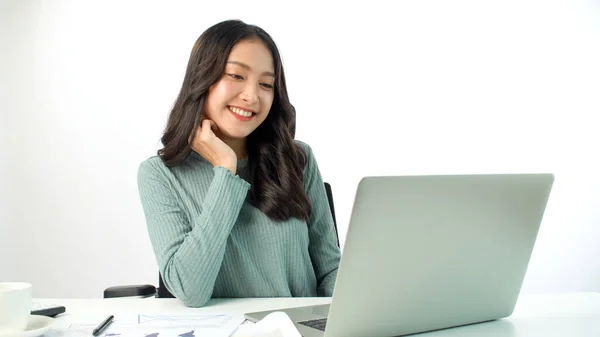 Cheerful freelance Asian woman thinking get idea work using laptop pc on desk over white background. Student young girl use computer think something comfortable network online over isolated.Technology