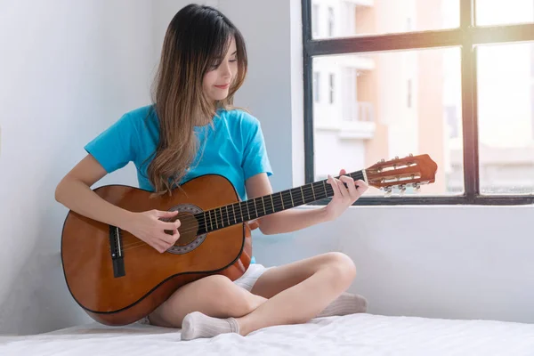 Cheerful Asian Woman Casual Playing Acoustic Guitar Sitting White Bed — Fotografia de Stock