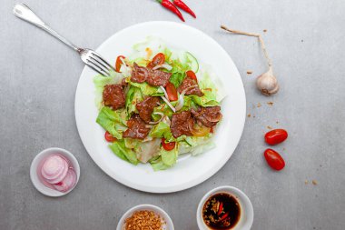 Vietnamese Salad Shaking Beef,  bowls, and plates with food top view