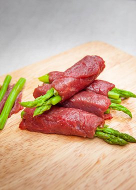 Grilled red beef meat rolls with asparagus, bowls, and plates with food top view