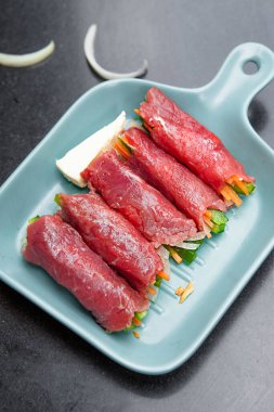 Grilled red beef meat rolls with asparagus, tomato,  bowls, and plates with food top view