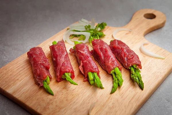 Grilled red beef meat rolls with asparagus, tomato,  bowls, and plates with food top view