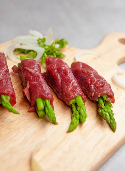 Grilled red beef meat rolls with asparagus, tomato,  bowls, and plates with food top view