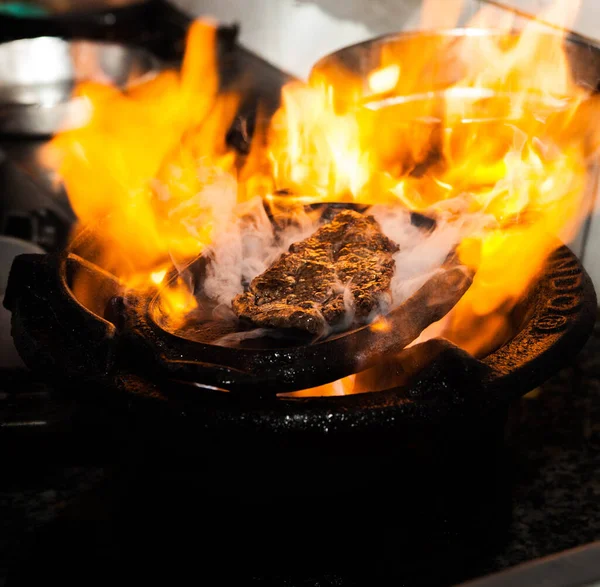 Beef steak with big fire, owls, and plates with food top view
