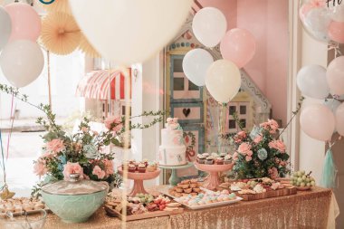 Basket of roses on the table at the party, Party decoration cupcakes, fruit mixes, candies