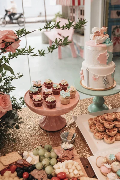 Basket of roses on the table at the party, Party decoration cupcakes, fruit mixes, candies