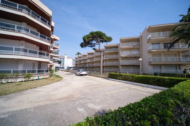 Yeşil ağaçları ve mavi gökyüzü olan modern bir apartman.