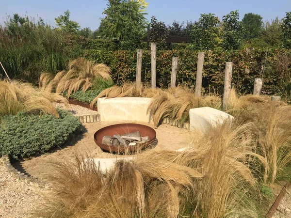 Modern summer patio. Lounge area in summer garden. Relaxing garden with swaying grasses, shell paths and fire place. Appeltern, Netherlands, September 16, 2020. Appeltern is the Netherlands' largest garden idea park.  