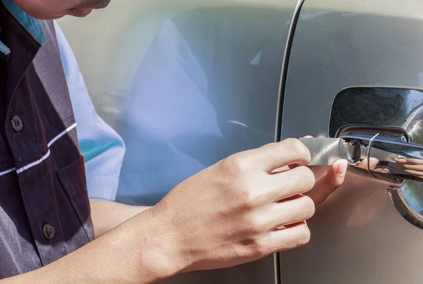 Close-up Of Person's Young Man Locksmith Hand Opening Bronze Car Door With Lock picker. Locksmith door opening device.