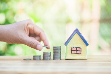 Erkeklerin eli sikkelerin üstündedir. Bir ev almak için tasarruf göstergesi. gayrımenkul merdiveni, ipotek, emlak yatırımları için konsept satın almak için madeni paralardan tasarruf parası planlamak.