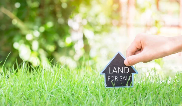 Konut inşaatı projesi. İnsanlar ev sembolünü pozisyon iğneleriyle ve satılık arazi ve emlak satışı veya emlak yatırımı konseptine yeşil çim sözleriyle birlikte koyuyorlar.,