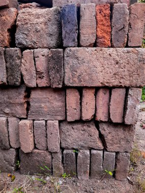 Portrait of a pile of bricks that have long been exposed to the sun and rain overgrown with small plants and moss, it is a building material made of burnt clay. 