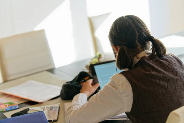 young women in business suit outfit sitting at table and using tablet computer and learning with some notice book and listens music