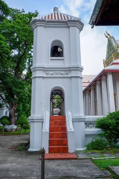 The bell tower has speakers to amplify the sound. red stairway Green tree background, white wall