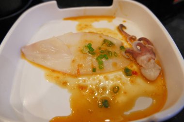 Beyaz tabakta soslu taze kalamar.