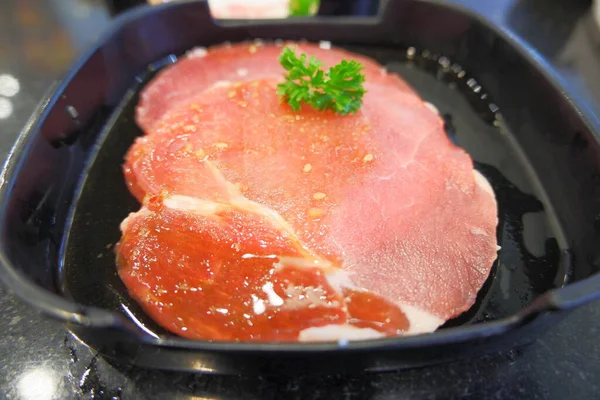 Raw beef with fat inserted, carved, placed in a black plate.