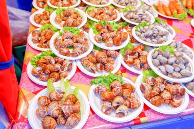 Sebzelerle süslenmiş kağıt tabağa konmuş kabuklu deniz ürünleri. Tayland 'da yiyecek bulmak kolay..