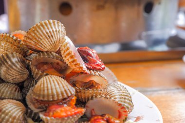 Buharda pişirilmiş midyeler (kaynamış midyeler) beyaz bir tabağa yerleştirilir. Dilimlenmiş domates, salatalık ve marulla süslenmiş..