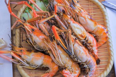 Izgara Büyük Nehir Karidesi. Salatalık ve marulla süslenmiş bambu bir tabağa yerleştirilmiş..