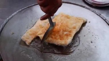 Tayland 'da sokak yemeği gevrek un roti büyük bir tavada şef roti hamuru kızartıyor.