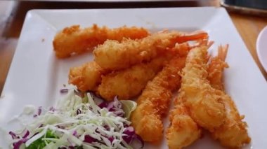 Tayland yemeği, karides, dışarıda ekmek kırıntıları olacak. karnabaharla süslenmiş beyaz bir tabağa yerleştirilmiş..