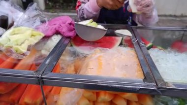Tayland sokak yemekleri Şef cam bir dolaptaki meyveleri kesiyor. İçinde seçebileceğin meyveler var..