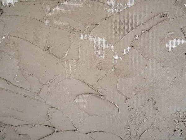 Plastering cement on a reinforcing plastic grid on a foam board